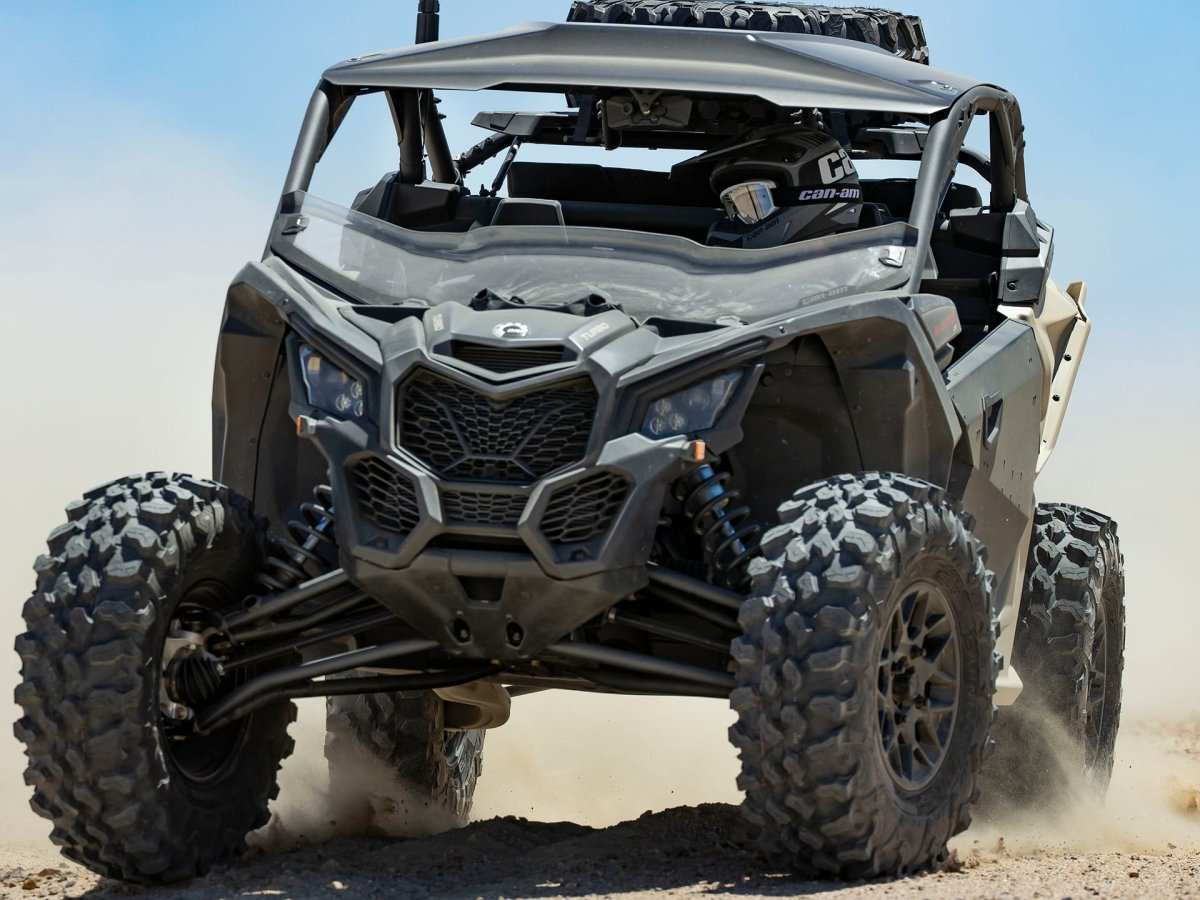 2022 Can-Am Maverick off-road side-by-side vehicle kicking up dust on rugged terrain