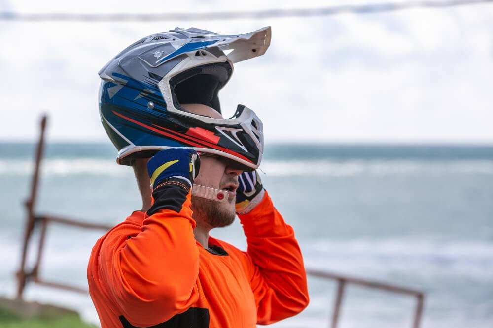 Motorcyclist wearing a blue and red full-face helmet with visor by the ocean representing California Motorcycle Helmet Visor Law