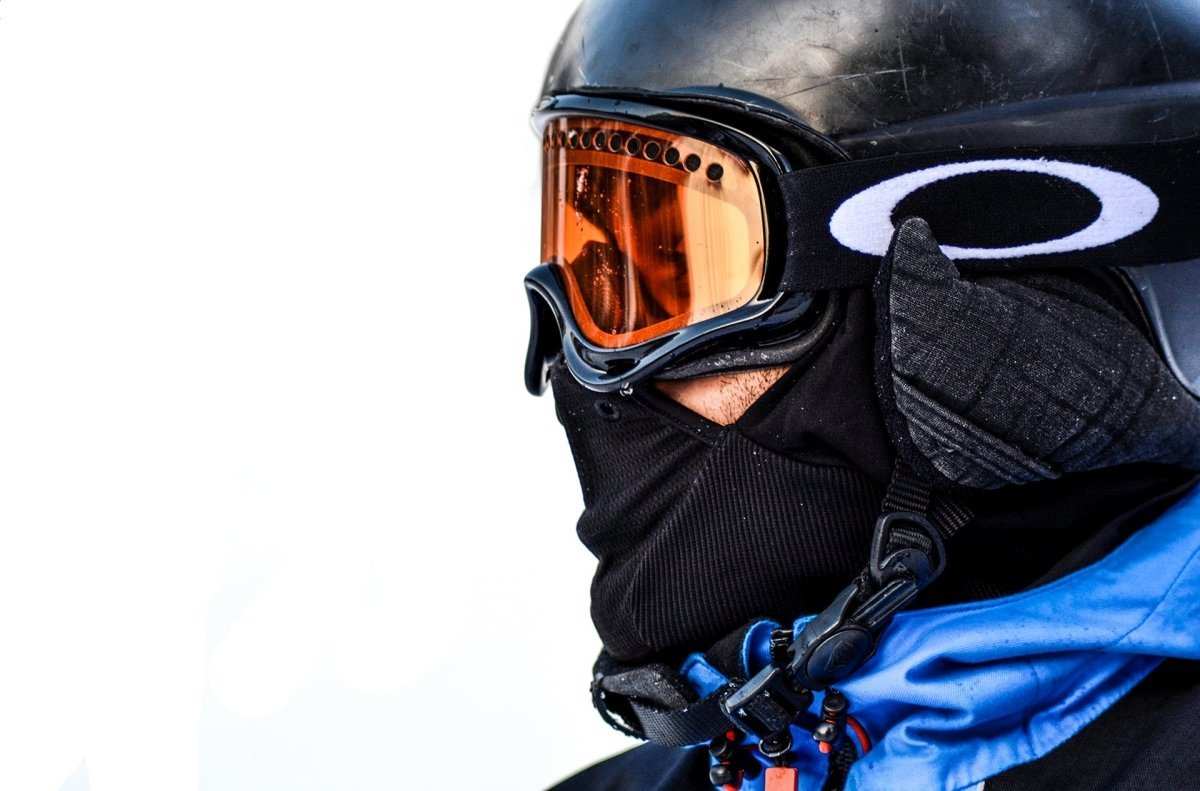 Close-up of a person wearing orange-tinted ATV goggles with a black helmet and face covering for UTV and ATV riding protection