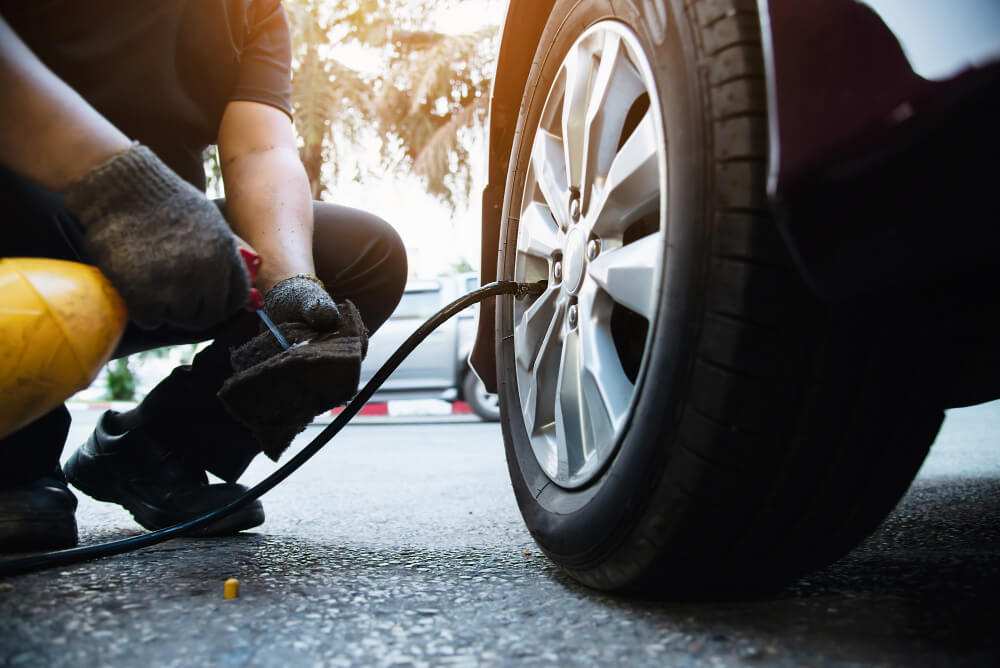 person inflating car tire with air pump showing wheel and tire close up