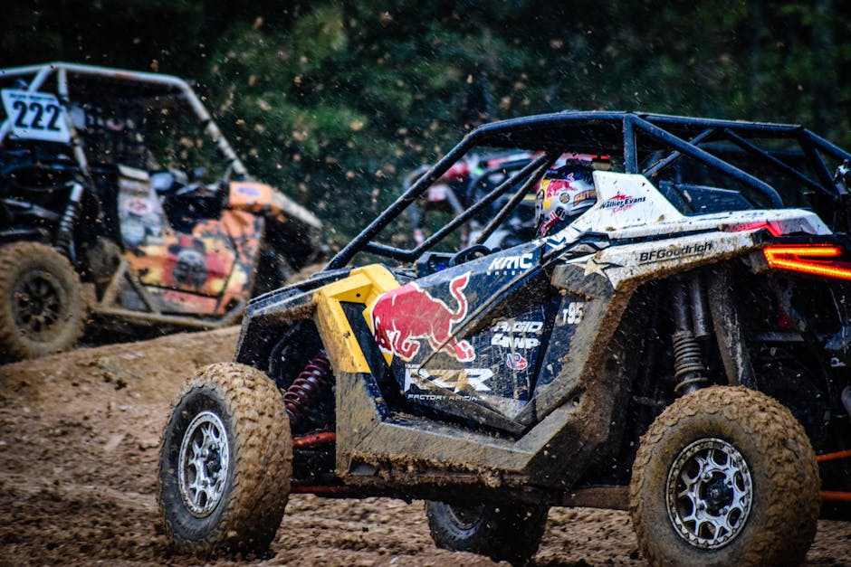 Off-road UTV side-by-side vehicles racing in muddy terrain with dirt flying