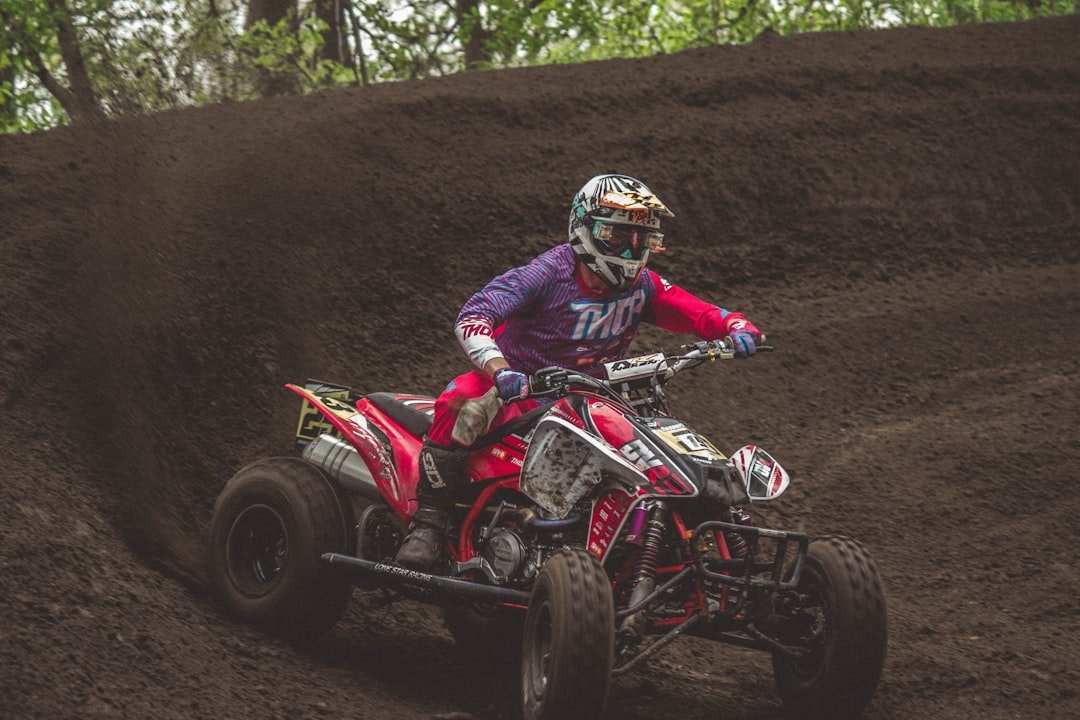 Off-road rider on a Honda Talon ATV racing through a dirt track, equipped with performance and protective Honda Talon accessories
