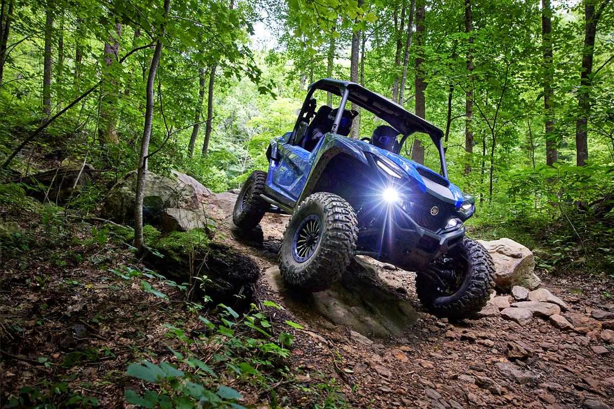 Yamaha RMAX Sport UTV navigating rocky forest trail with headlights on