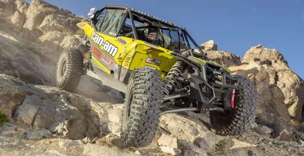 Off-road UTV equipped with Maxxis Carnivore tires climbing rocky terrain