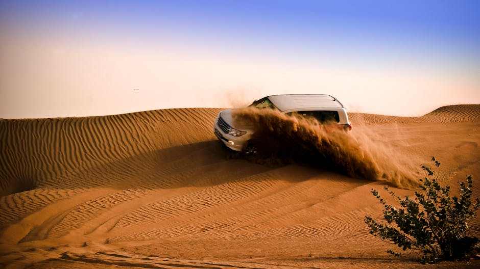 Off-road vehicle driving through sand dunes kicking up dust, demonstrating Maverick R suspension performance