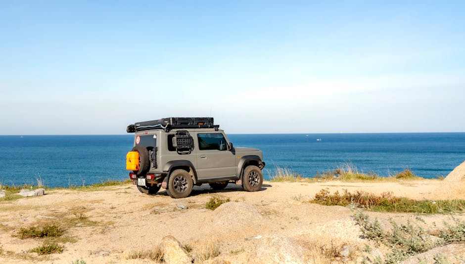 Off-road vehicle equipped with essential UTV hitch accessories parked by the ocean with clear blue sky background