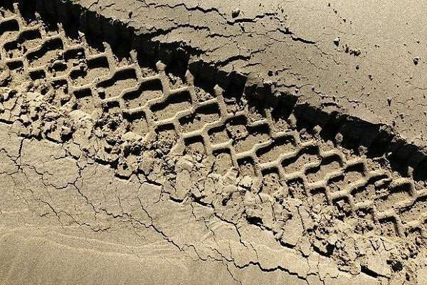 Close-up of deep tire tracks in muddy terrain representing off-road vehicles UTV vs ATV comparison